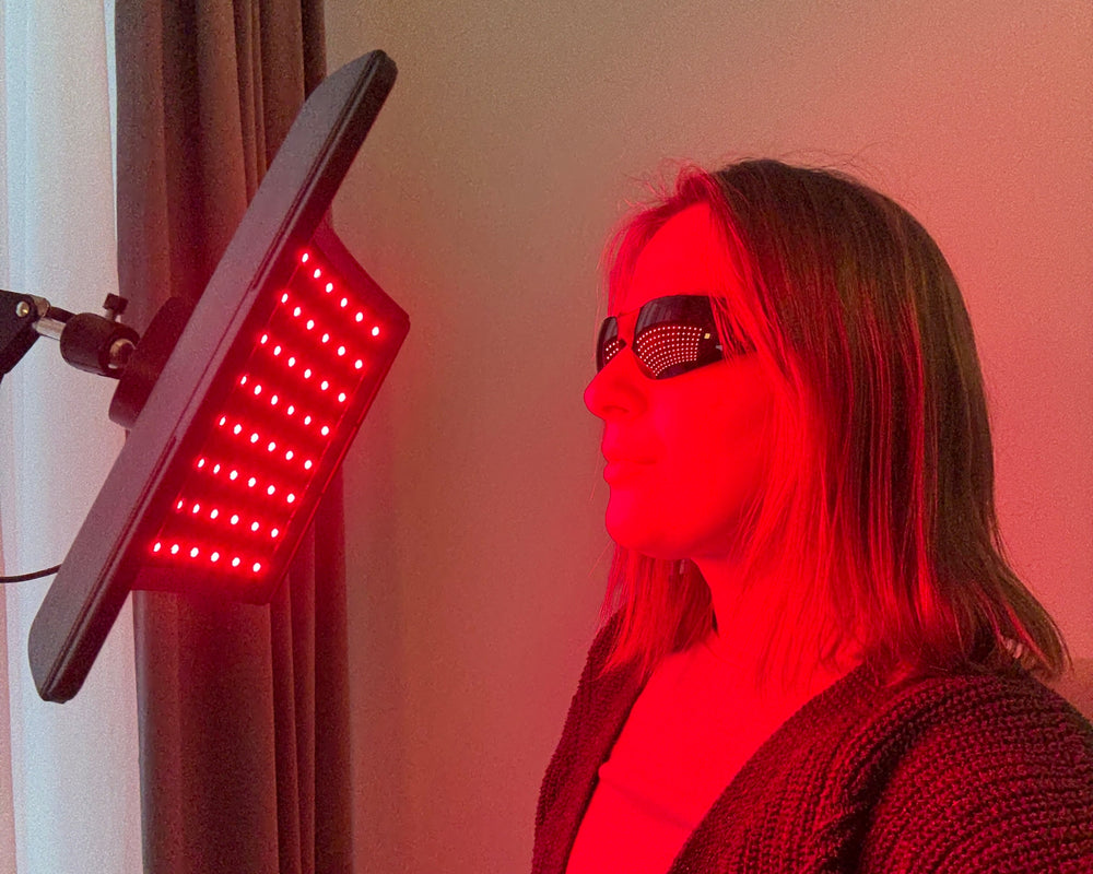 Person receiving red light therapy under a LED panel.
